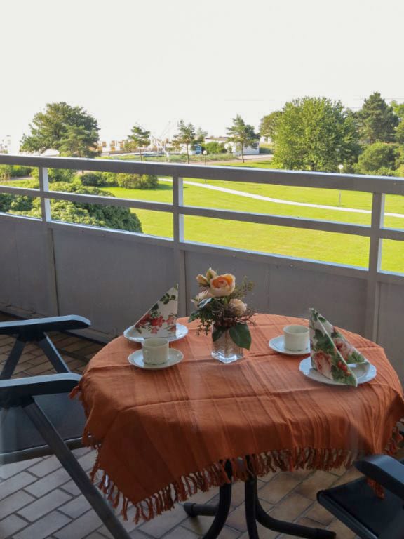 Balkon mit rundem Tisch, gedeckt für zwei Personen, zwei Stühlen und Blick auf die Rasenfläche